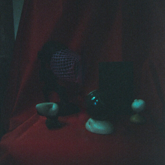 An underexposed photo of small sculptures are arranged against a red velvet cloth backdrop.